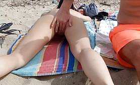 Sunbathing babe gets fingered, and her pussy played with by her husband on a nude beach, sexy brunette orgasms right in her husband's hand. 